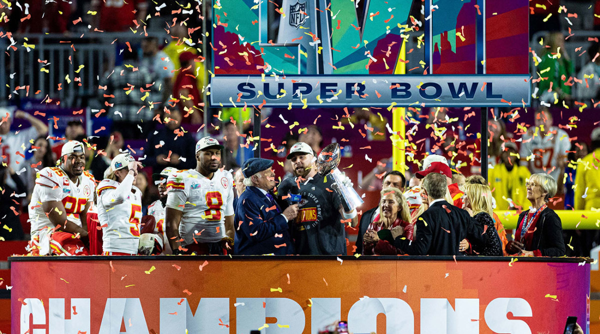 Travis Kelce holds the Lombardi Trophy on a stage after the Chiefs win the Super Bowl